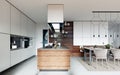 Large kitchen in a modern Scandinavian style, white and wooden furniture facade. Large kitchen island with a hood over it