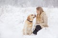 A large labrador dog and a cat in winter on a walk with a young woman in a snowy field Royalty Free Stock Photo