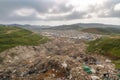 large landfill, with rows of garbage and recycling bins, surrounded by green landscape