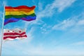 large lgbt flag and flag of the District of Columbia state, USA waving in the wind at cloudy sky. Freedom and love concept. Pride