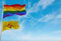 large lgbt flag and flag of New Mexico state, USA waving in the wind at cloudy sky. Freedom and love concept. Pride month.