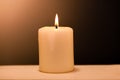 Large lighted candle on a shade background