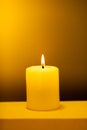 Large lighted candle on a warm yellow background