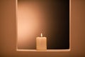 Large lighted candle on a shade background