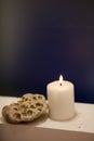 Large lighted candle on a shade blue background