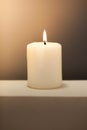 Large lighted candle on a shade contrast background