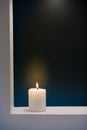 Large lighted candle on a shade contrast background