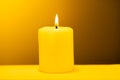 Large lighted candle on a warm yellow background