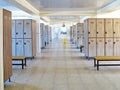 Large locker room with lockers and benches on the floor tiled. The clock hangs on the wall