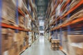 Large Logistics hangar warehouse with lots shelves or racks with pallets of goods, perspective with motion blur effect