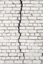 A large long crack in a white brick wall