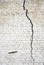 A large long crack in a white brick wall Royalty Free Stock Photo