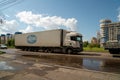 A large lorry, with an inscription in Russian - Drinking water Lel, is driving along a city street after a rain in summer Royalty Free Stock Photo