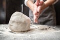 Large lump of kneaded dough on the table with flour, in the background of the baker hands. Bread making.
