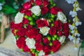Large, lush, beautiful, fragrant, delicate wedding bouquet close-up of white and red roses and green berries on a wooden surface. Royalty Free Stock Photo