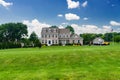 Large, luxurious, brick house with landscaping and a huge green lawn. Landscape on a summer sunny day under a blue cloudy sky