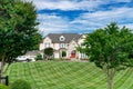 Large, luxurious, brick two-story large family home with landscaping and a huge green lawn. Landscape on a summer sunny day under