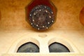Large luxurious brown Arab chandelier with candles and patterns and ornaments on the high stone ceiling of an ancient temple with