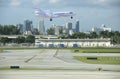 Large luxury commercial passenger private jet plane landing at Fort Lauderdale International Airport with cityscape in background