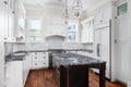 A large luxury white kitchen with black counter tops.