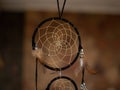 Large magical dream catcher of dark color with beige feathers.