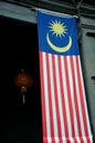 Large Malaysia flag hangs in doorway with red Chinese lantern in back
