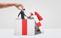 A large male hand getting a tiny businessman out from a white gift box with a red bow on white background. Royalty Free Stock Photo