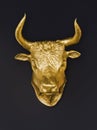 Large manacing golden bull head idol on dark background