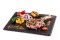 Large meat steak on the bone, grilled, served with grilled vegetables, corn, red onion, sweet peppers, potatoes. Modern serving