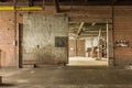 Large metal barn door left open in the basement level of an abandoned factory