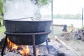 Large metal cauldron over a fire. A tourist fire on which water is boiled for food. Camp pot, boiling water, tourist food. Boiling