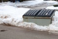 A large metal garbage bin sits on the side of a street in a condo corporation