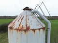 Large, metal grain feed silo showing a  poor state of repair. Royalty Free Stock Photo