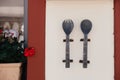 Large metal and old spoon and fork with carvings and patterns on them hang on the wall of cafe or restaurant on Santorini island, Royalty Free Stock Photo
