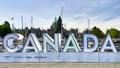 A large metal sign in block letters that spells out Canada at the inner harbor in Victoria, BC.