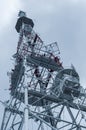 Large metal tower with various radio equipment, metal structure close-up, bottom up view.