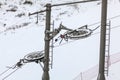 Large metal wheels for steel cables on top of ski lift supporting pillar, snow covered piste in background Royalty Free Stock Photo