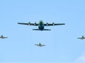 Large military cargo plane flying over Bucharest, escorted by three fighter planes Royalty Free Stock Photo
