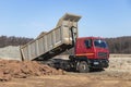 A large mining truck unloads the earth. A soil transporter with a raised body dumps soil