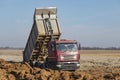 A large mining truck unloads the earth. A soil transporter with a raised body dumps soil