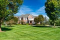 Large modern brick house with colonial style balcony. Single family home with large mowed lawn and beautiful landscaping. Sunny Royalty Free Stock Photo