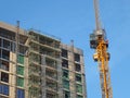 large modern building under construction covered in scaffolding with a tower crane against a bright blue sky Royalty Free Stock Photo