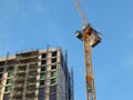 Large modern building under construction covered in scaffolding with a tower crane against a bright blue sky Royalty Free Stock Photo