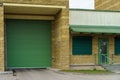 A large modern garage made of beige brick and green roller gates. Video surveillance system at the entrance to the garage. Safe Royalty Free Stock Photo