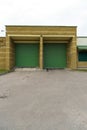 A large modern garage made of beige brick and green roller gates. Video surveillance system at the entrance to the garage. Safe Royalty Free Stock Photo