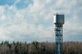 large modern high water tower on sky background with clouds. Forest on the horizon Royalty Free Stock Photo