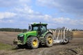 A large modern John Deere tractor tows a cultivator in a field