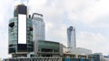 A large, modern office building with a blank billboard in front of it. The billboard is white and has a black frame is located in Royalty Free Stock Photo