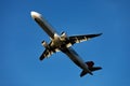 A large modern plane flies in the sky, a view from below from the ground to the belly of the aircraft.