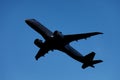 A large modern plane flies in the sky, a view from below from the ground to the belly of the aircraft.